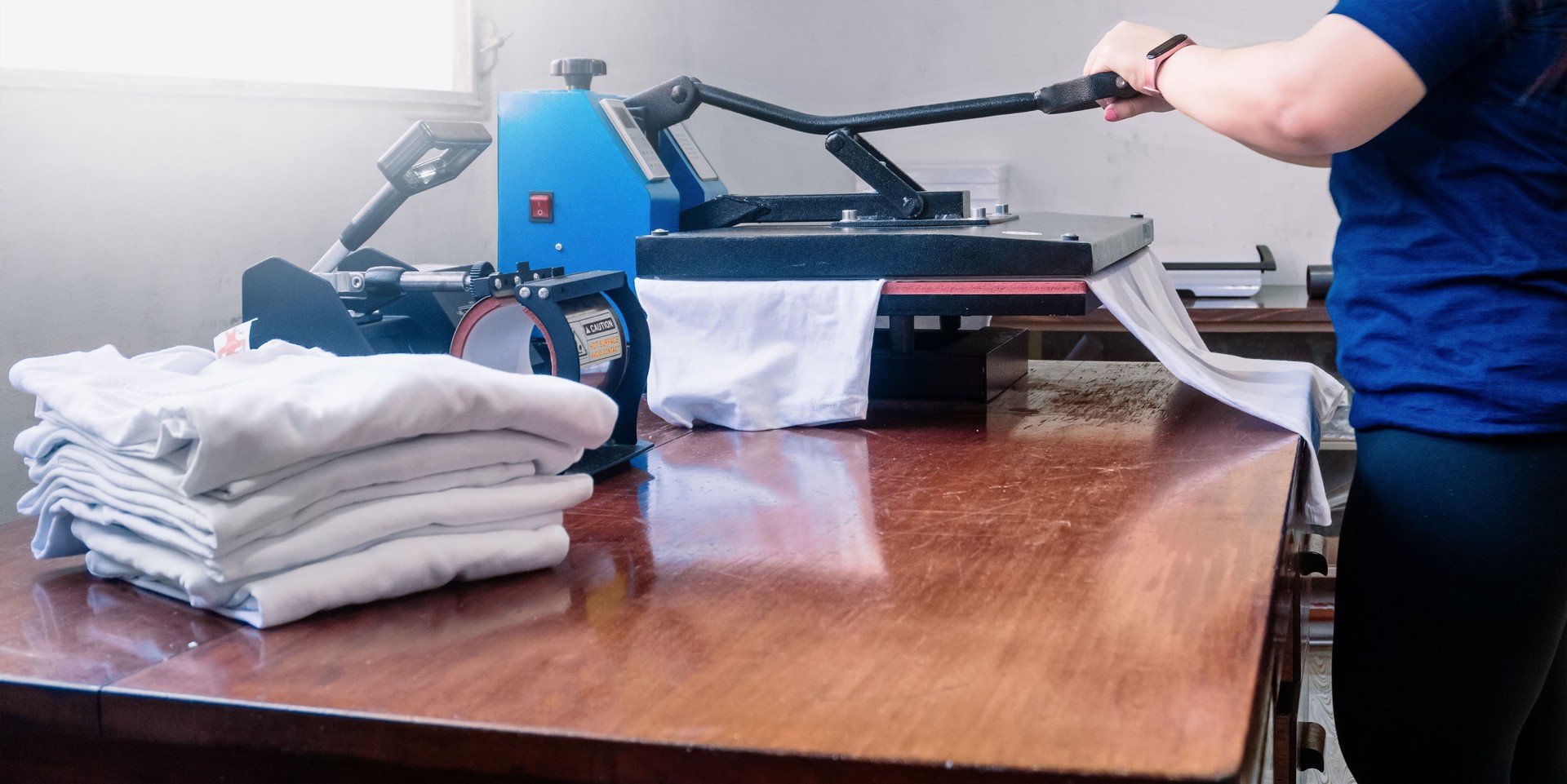 woman manipulating a sublimation machine ironing a shirt. advertising and screen printing concept.